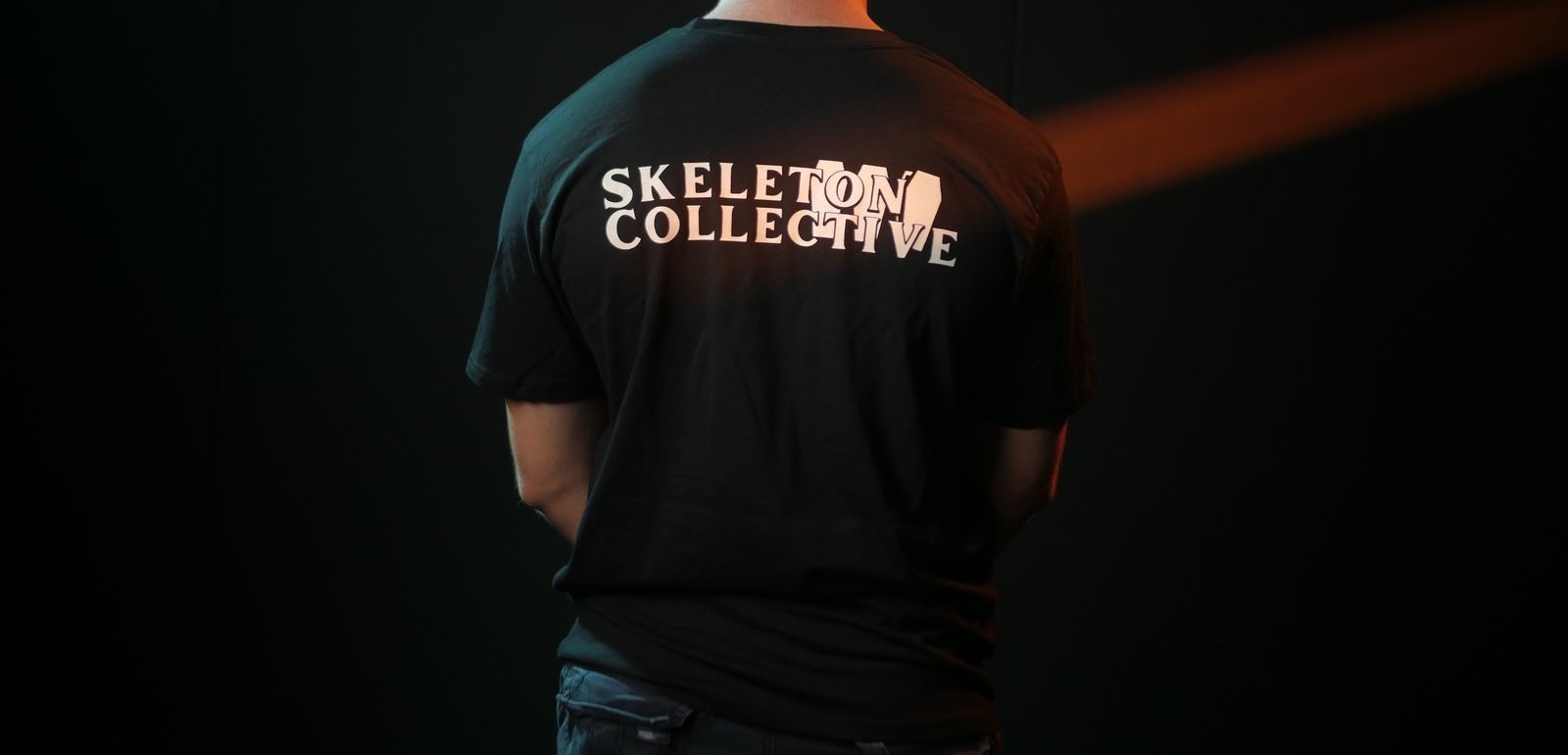 Back of the Skeleton Collective heavyweight black crew t-shirt, the studio wordmark with a coffin set into the lettering.